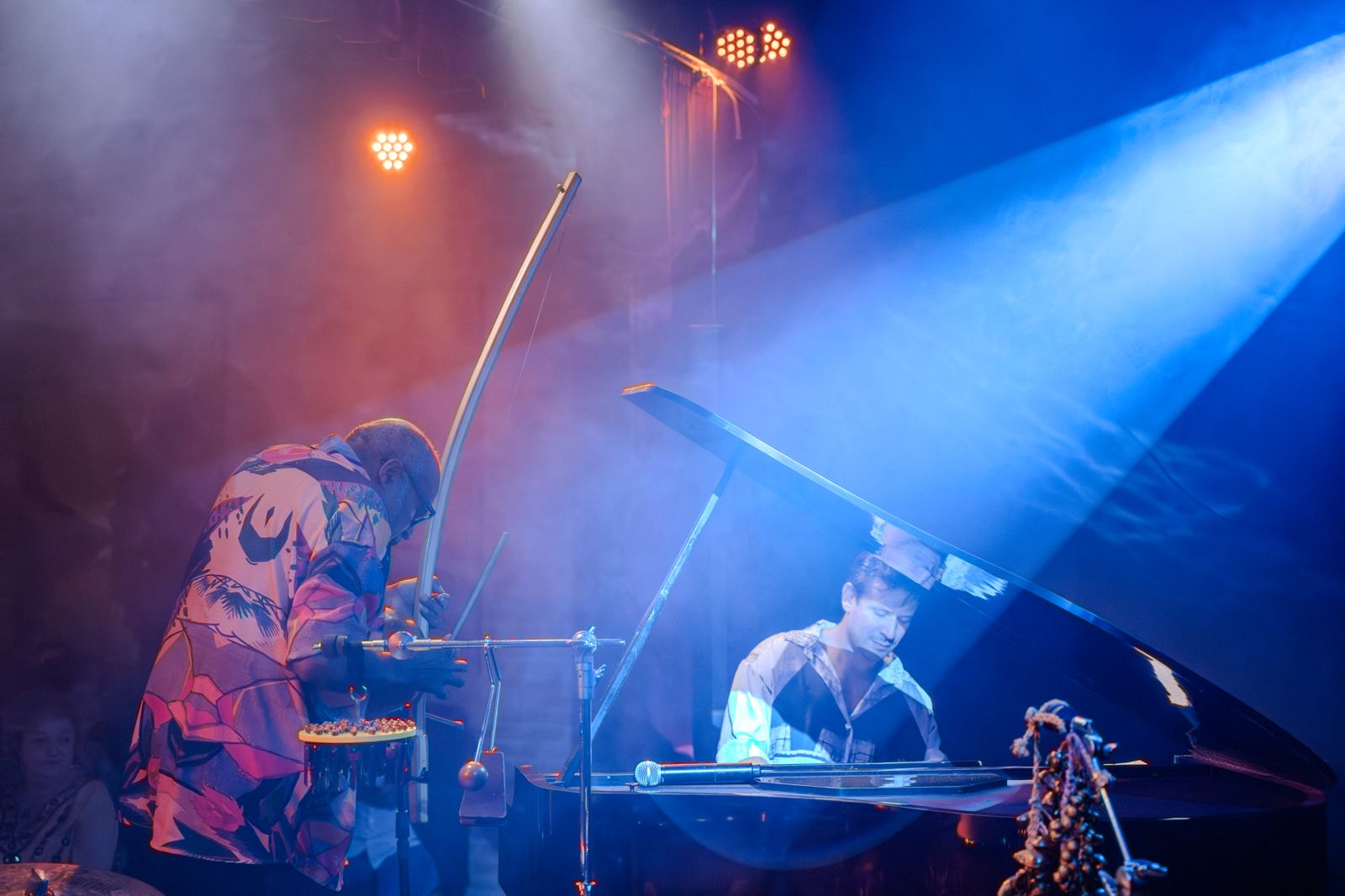 Percussionista e pianista se apresentam sob luz azul