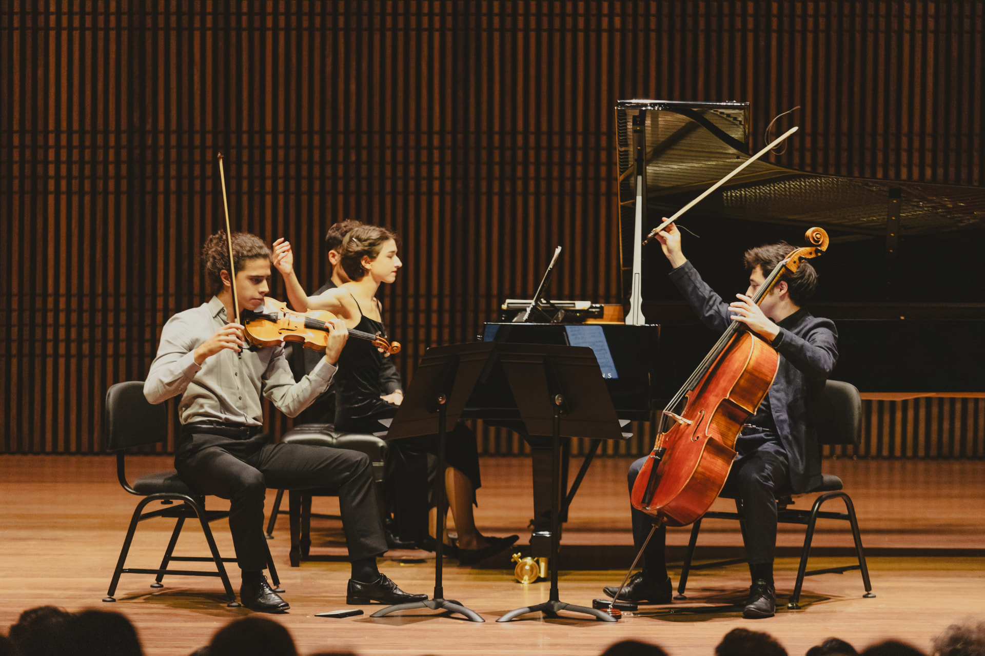 Trio de câmara com violino, piano e violoncelo no palco